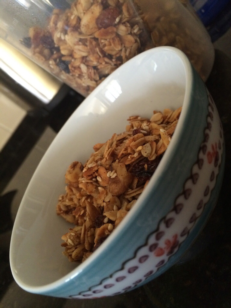 granola in a decorative cereal bowl with a container of granola behind