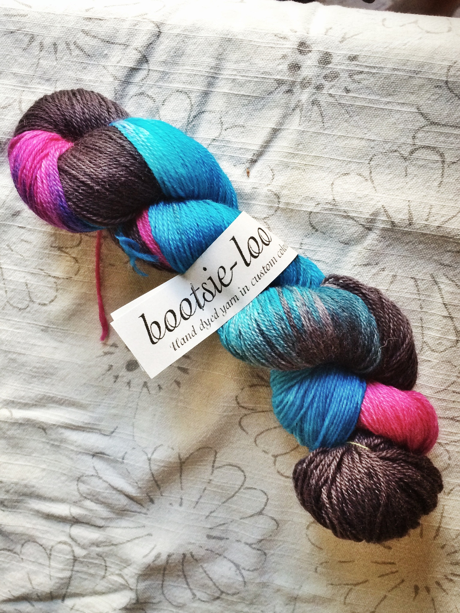 Fingering weight yarn in blue, pink, and grey from Studioloo